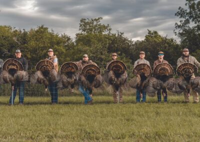 Several people gather in a field, each holding a turkey, symbolizing community and celebration during the holiday season.